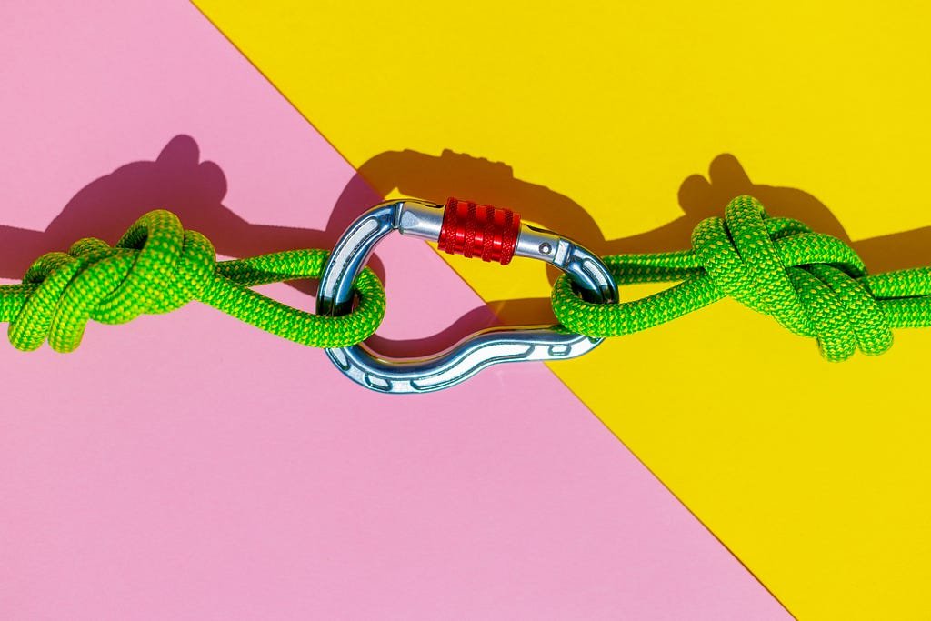 Rope with a secure knot and a carabiner lies on a colored background.
