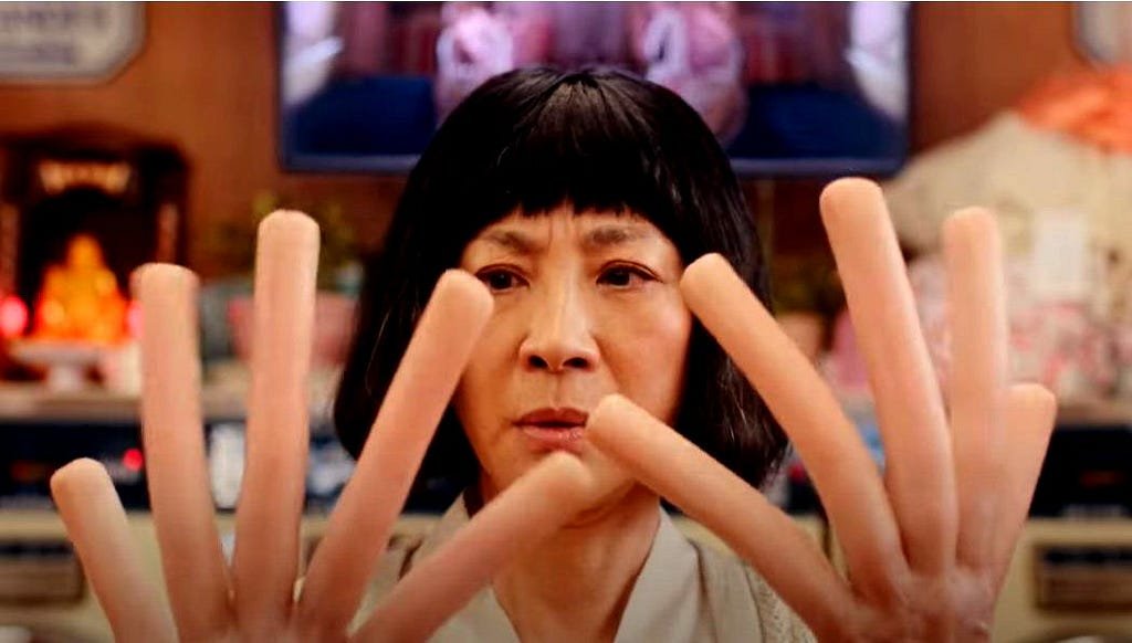 Image from the film Everything Everywhere All at Once where Michelle Yeoh’s hands have become hot dogs
