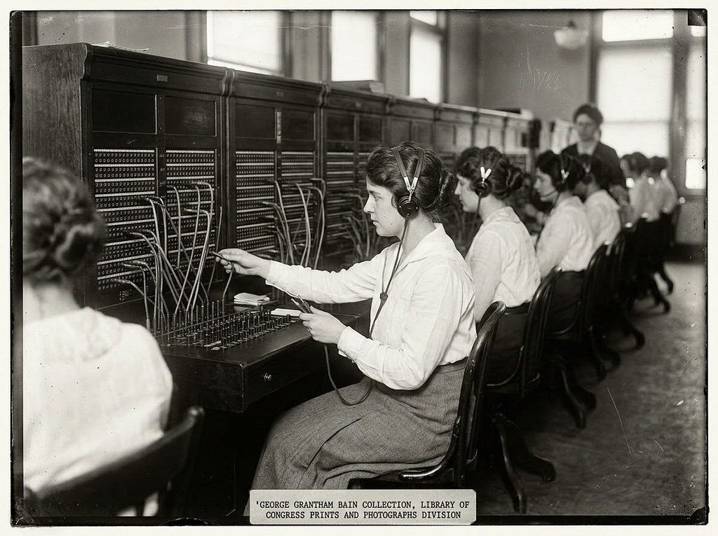 A photograph of a real network operations center: rows of staffed workstations facing large wall-mounted monitors displaying system dashboards.A black-and-white archival photograph of 1920s telephone switchboard operators, women seated in a row at a wall of plug-and-cord switchboards, connecting calls by hand.